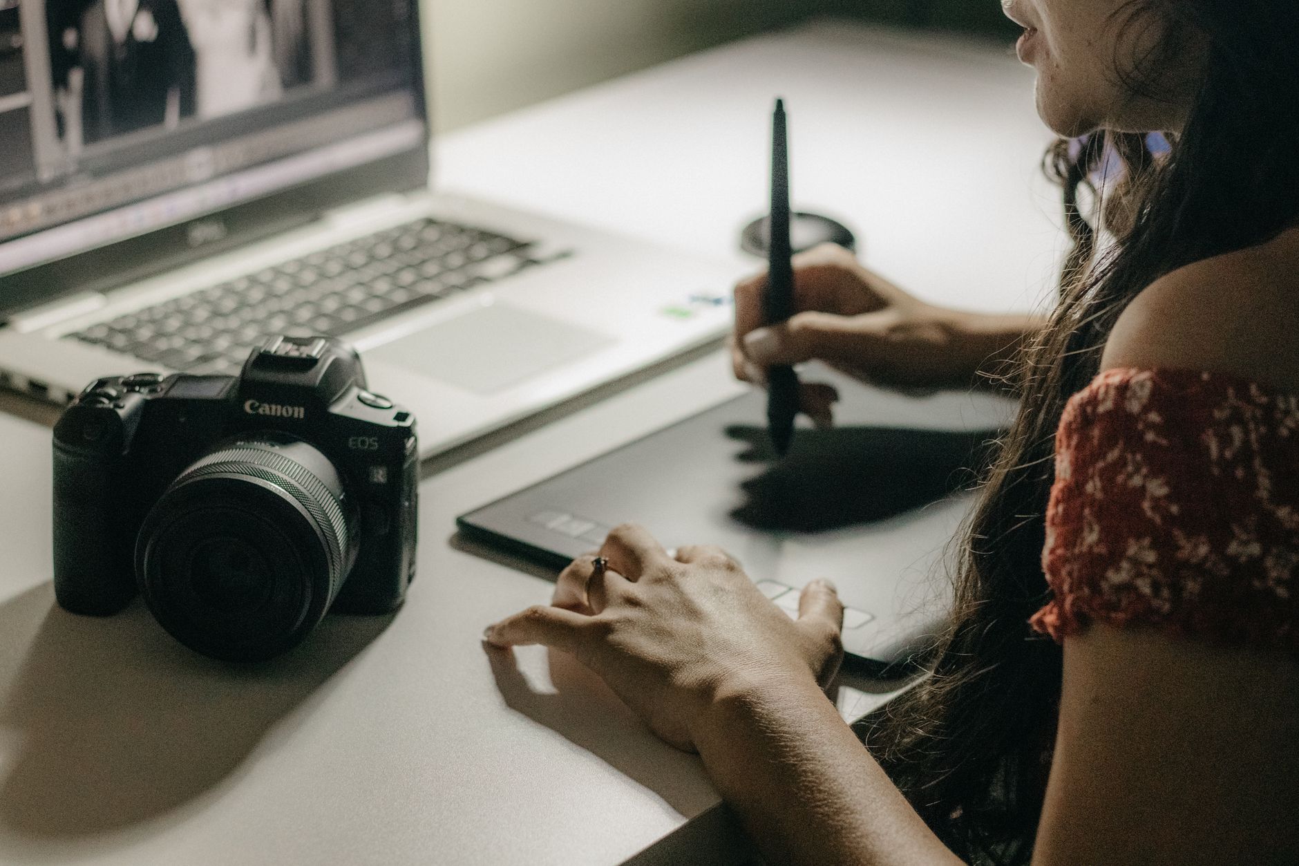 Kobieta obrabia zdjęcia w Photoshopie na laptopie z tabletem i aparatem