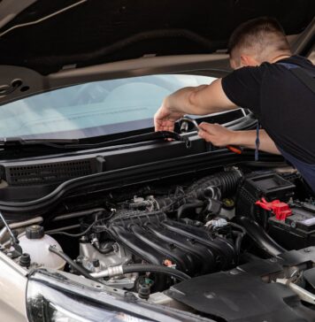 Mechanik naprawia silnik samochodu na zewnątrz w słoneczny dzień