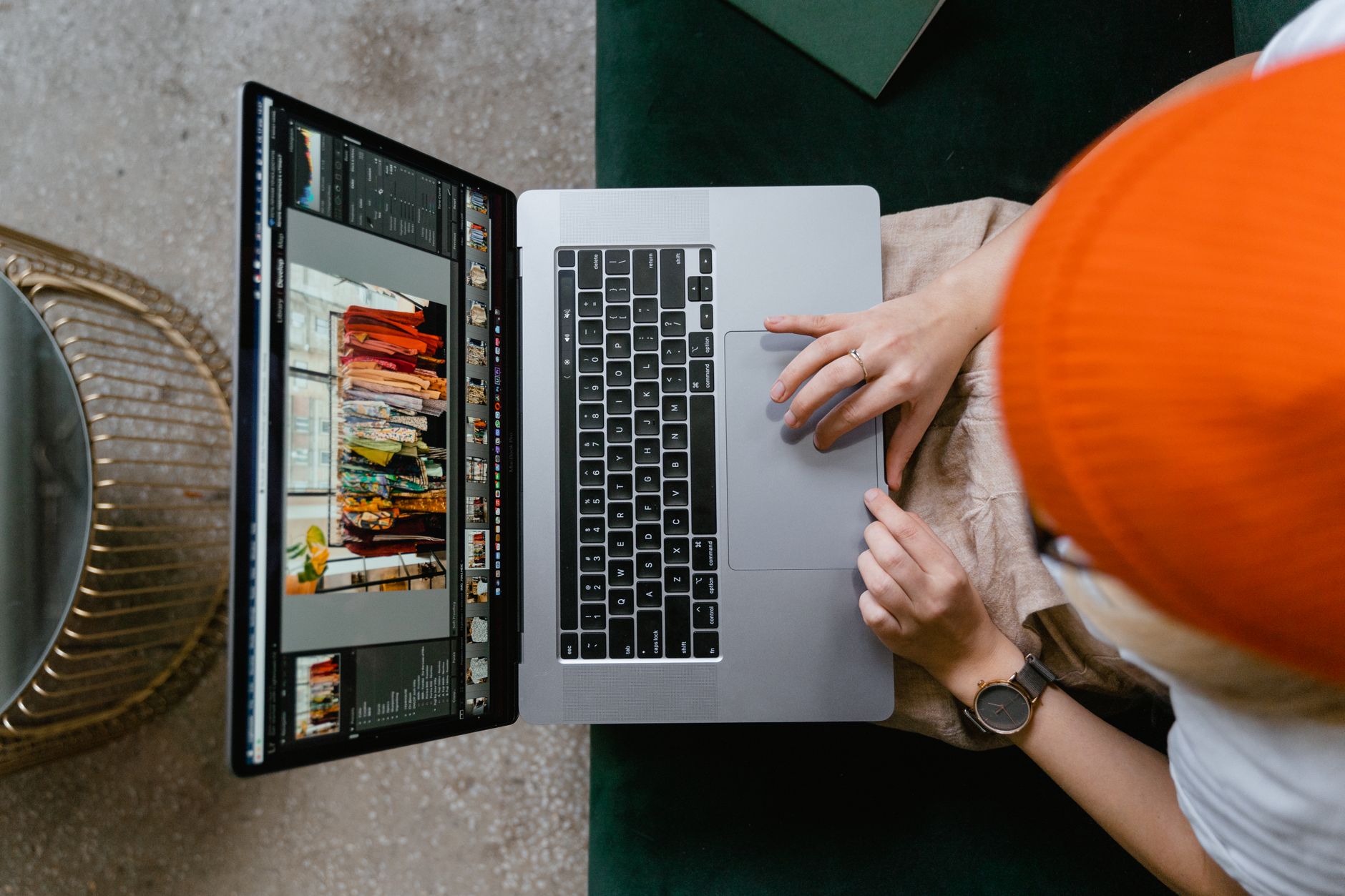 Osoba w pomarańczowej czapce edytuje zdjęcia w programie graficznym na laptopie