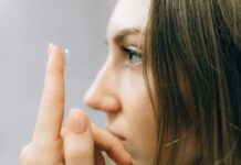 Soczewki kontaktowe dla wrażliwych oczu – jak dobrać komfortowe rozwiązanie z pomocą optometrysty Młoda kobieta zakłada soczewkę kontaktową na oko z bliska