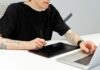 Od szkicu na kartce do cyfrowego muralu: workflow z wykorzystaniem AI Tatuażysta pracuje przy tablecie graficznym i laptopie w pracowni