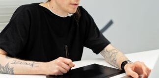 Tatuażysta pracuje przy tablecie graficznym i laptopie w pracowni
