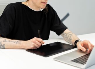 Od szkicu na kartce do cyfrowego muralu: workflow z wykorzystaniem AI Tatuażysta pracuje przy tablecie graficznym i laptopie w pracowni